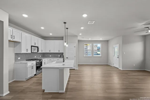 a large kitchen with stainless steel appliances kitchen island a large counter top and a wooden floors