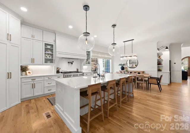 a large kitchen with white cabinets a sink dishwasher and a dining table with chairs