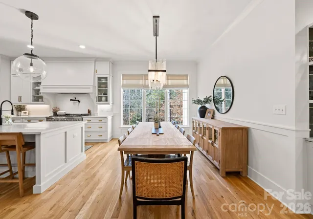 a view of a kitchen with granite countertop a stove a sink a refrigerator and a dining table with wooden floor