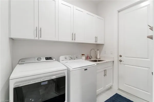 a large white kitchen with a stove a sink a refrigerator and a fireplace