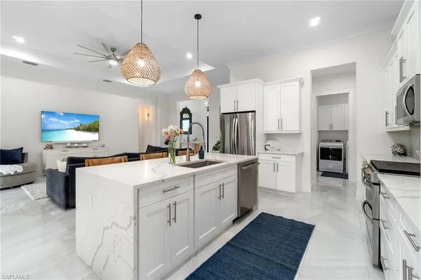 a view of a white house with a big yard and potted plants and large trees