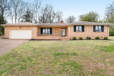 a front view of house with yard and trees in the background