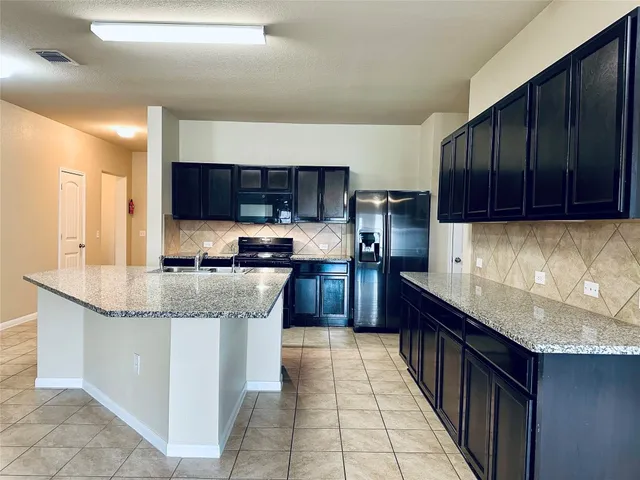 a kitchen with stainless steel appliances granite countertop a stove a sink and a microwave