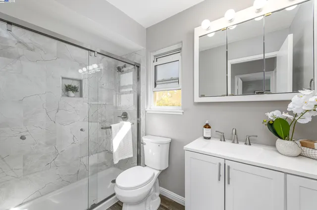 a bathroom with a granite countertop sink a toilet and shower