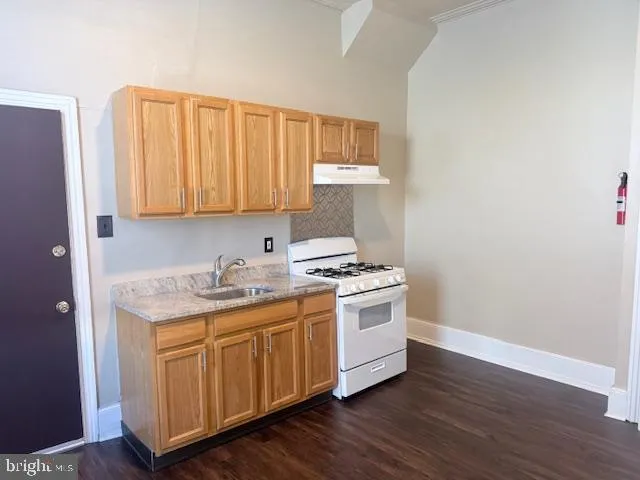 a kitchen with a stove and wooden floor