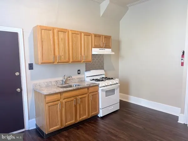a kitchen with a stove and wooden floor