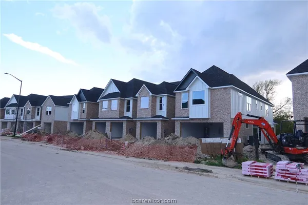 a view of a white house next to a road with big trees