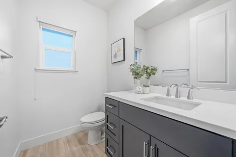 a bathroom with a granite countertop toilet a sink and a mirror