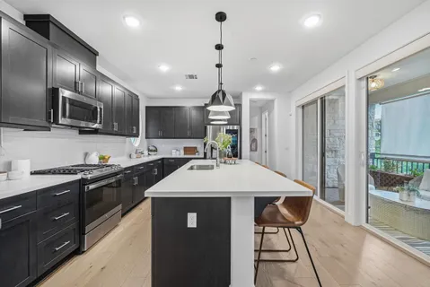 a kitchen with kitchen island granite countertop stainless steel appliances lots of counter space a sink refrigerator and cabinets