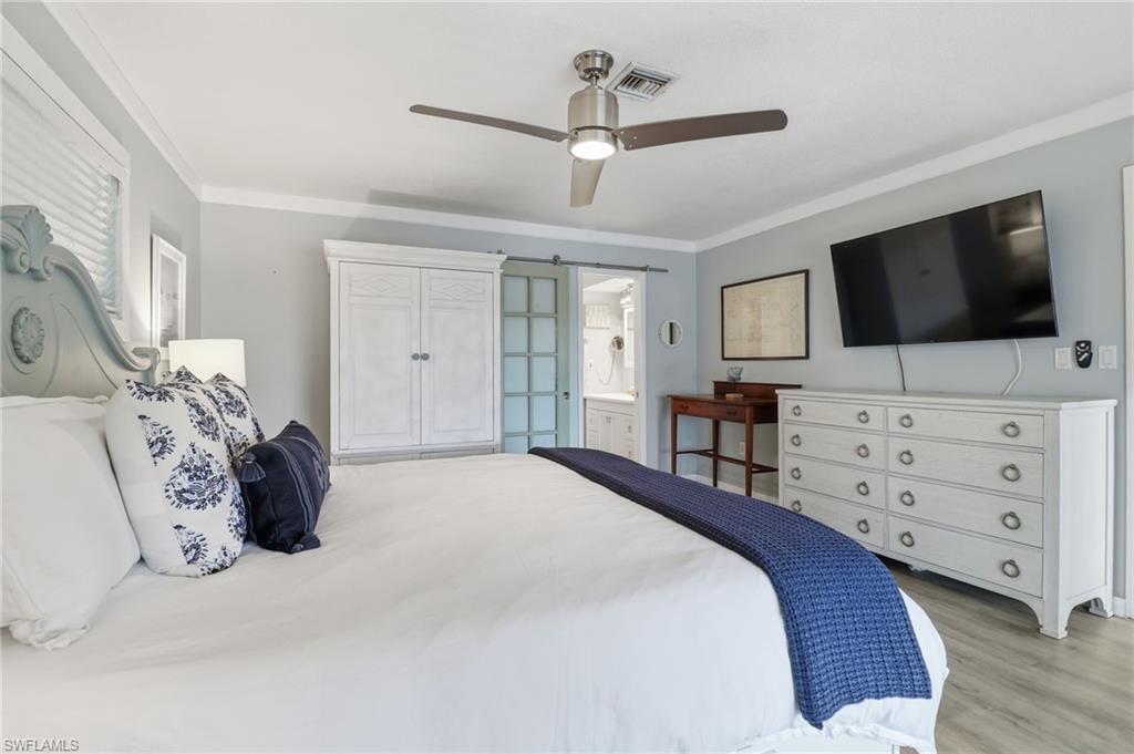 2211 Bayview Road Punta Gorda, FL 33950 - Photo 27 of 37 Bedroom featuring crown molding, a ceiling fan, light wood-type flooring, and connected bathroom