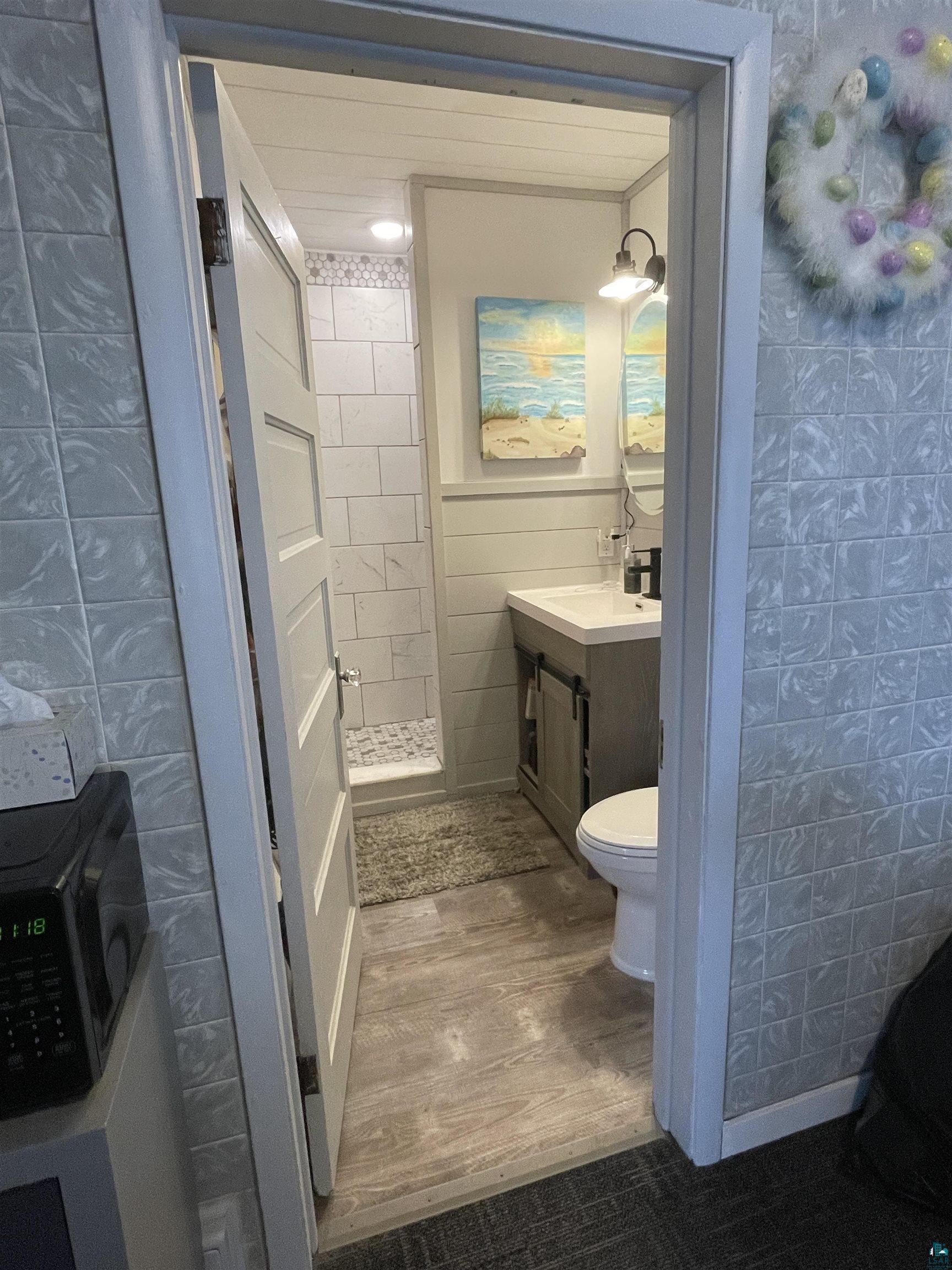 203 3rd Street South Virginia, MN 55792 - Photo 6 of 22 Bathroom featuring tile walls, vanity, a shower stall, and dark wood finished floors