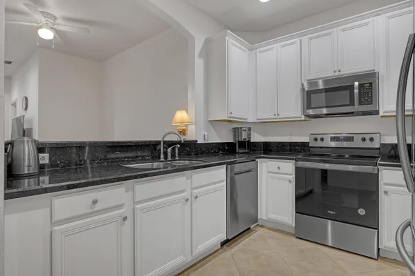 a kitchen with granite countertop white cabinets stainless steel appliances and a sink