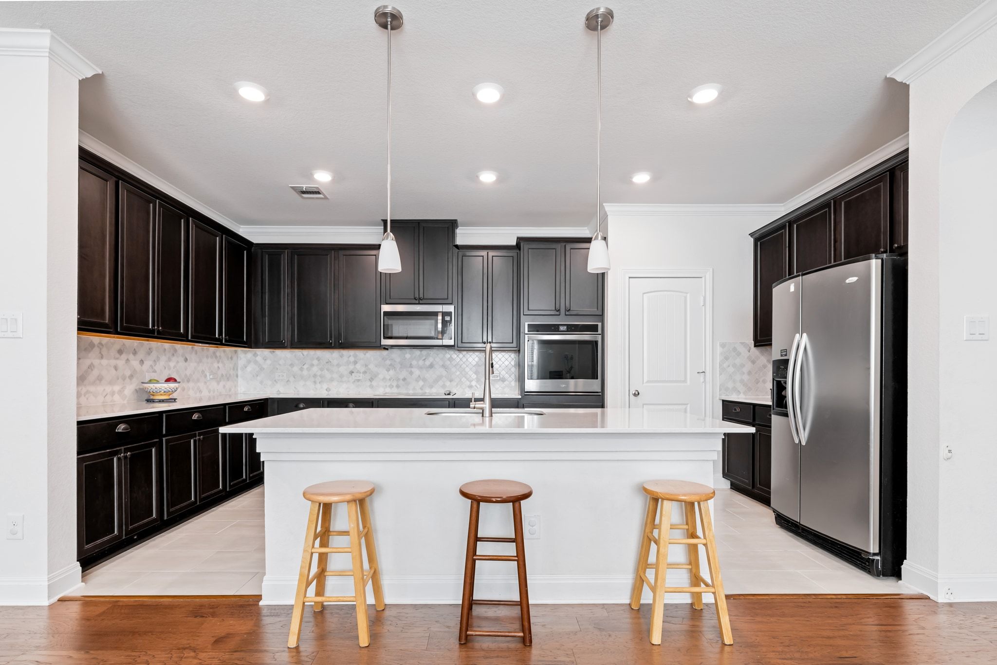 1022 Toltec Trail Georgetown, TX 78626 - Photo 11 of 37 Kitchen featuring backsplash, crown molding, a kitchen bar, appliances with stainless steel finishes, and pendant lighting