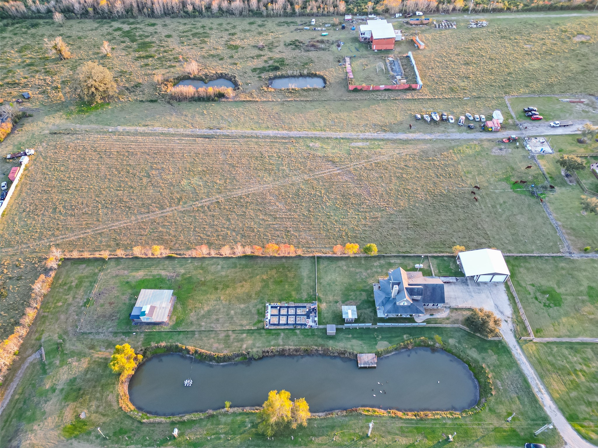912 County Road 340 Angleton, TX 77515 - Photo 46 of 50 This aerial photo showcases a spacious rural property with a house, a pond, and several outbuildings. The land is expansive and open, offering plenty of space for outdoor activities and potential farming. The property is surrounded by fields and trees, providing a peaceful and private setting.