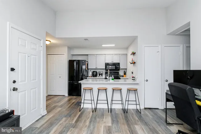 a kitchen with stainless steel appliances a dining table chairs a refrigerator and cabinets