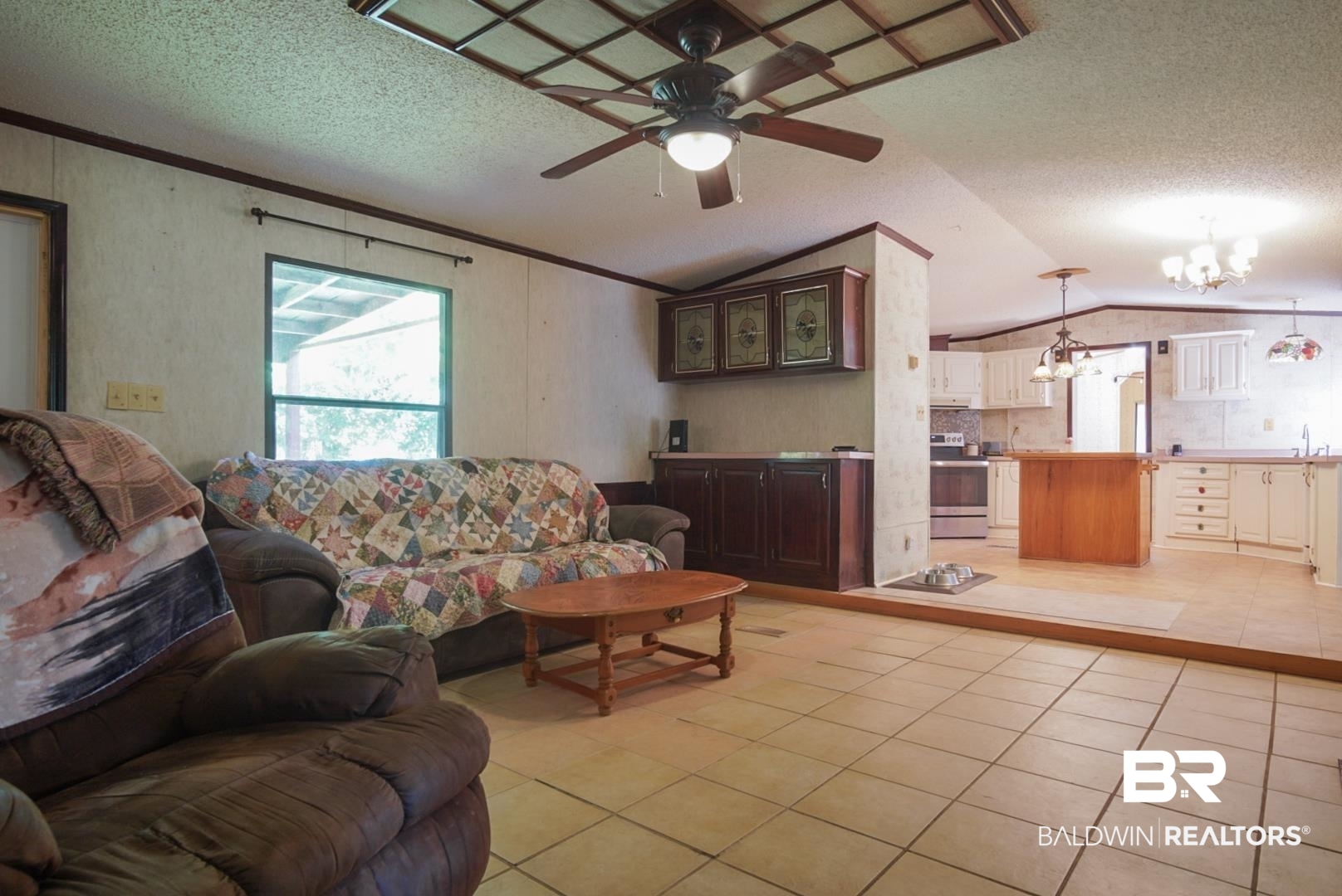 9190 County Road 97 Elberta, AL 36530 - Photo 25 of 53 Living room with ceiling fan with notable chandelier, vaulted ceiling, crown molding, and light tile patterned floors