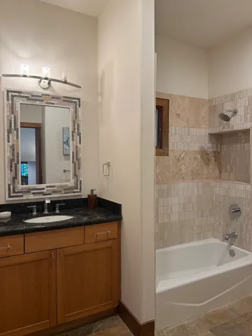 a bathroom with a granite countertop sink a toilet mirror and bathtub