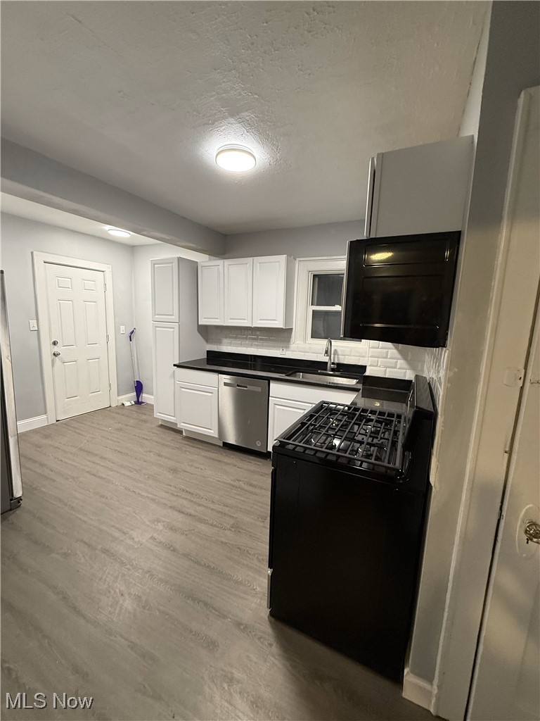 1013 Berwin Street Akron, OH 44310 - Photo 9 of 13 Kitchen with black electric range oven, white cabinets, sink, stainless steel dishwasher, and light wood-type flooring