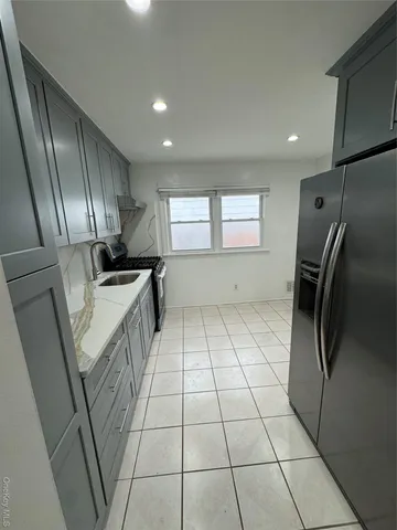 a kitchen with granite countertop a refrigerator a sink a counter top space and cabinets