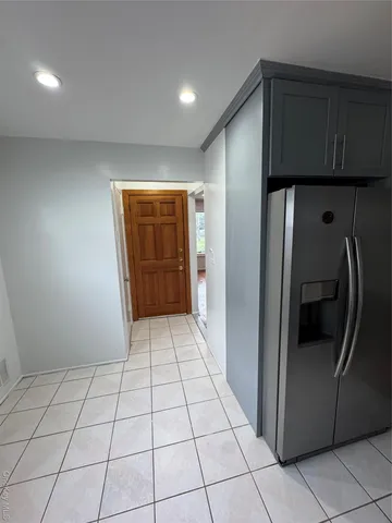 a view of a refrigerator in kitchen and an empty room in wooden floor