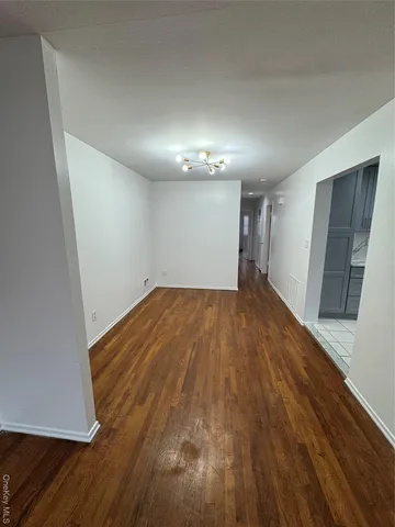 an empty room with wooden floor and hallway
