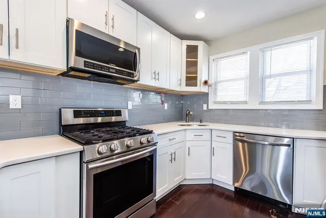 a kitchen with cabinets stainless steel appliances and wooden floor