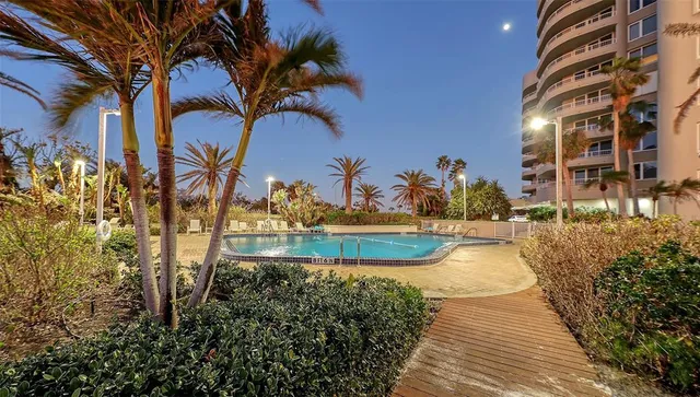a view of a swimming pool with a lawn chairs under an umbrella