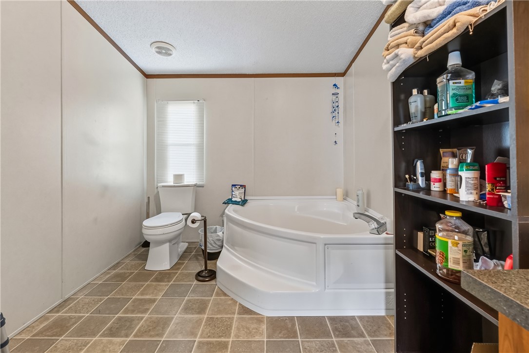 1905 Bethany Church Road Belton, SC 29627 - Photo 15 of 20 Tiled flooring anchors this spacious bathroom featuring a deep corner soaking tub and built-in shelving.