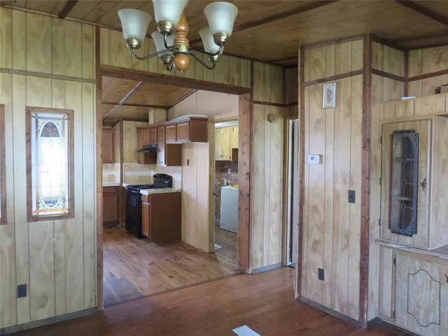 a view of a hallway with wooden floor and a kitchen