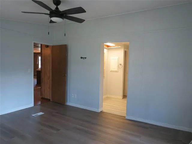 an empty room with wooden floor cabinet and windows