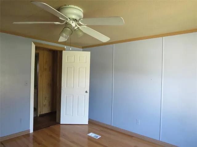 an empty room with a ceiling fan and wooden floor