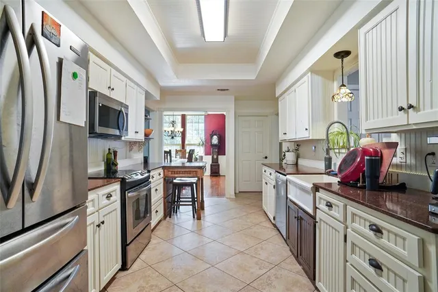 a kitchen with stainless steel appliances granite countertop a refrigerator a stove top oven a sink a dining table and chairs with wooden floor