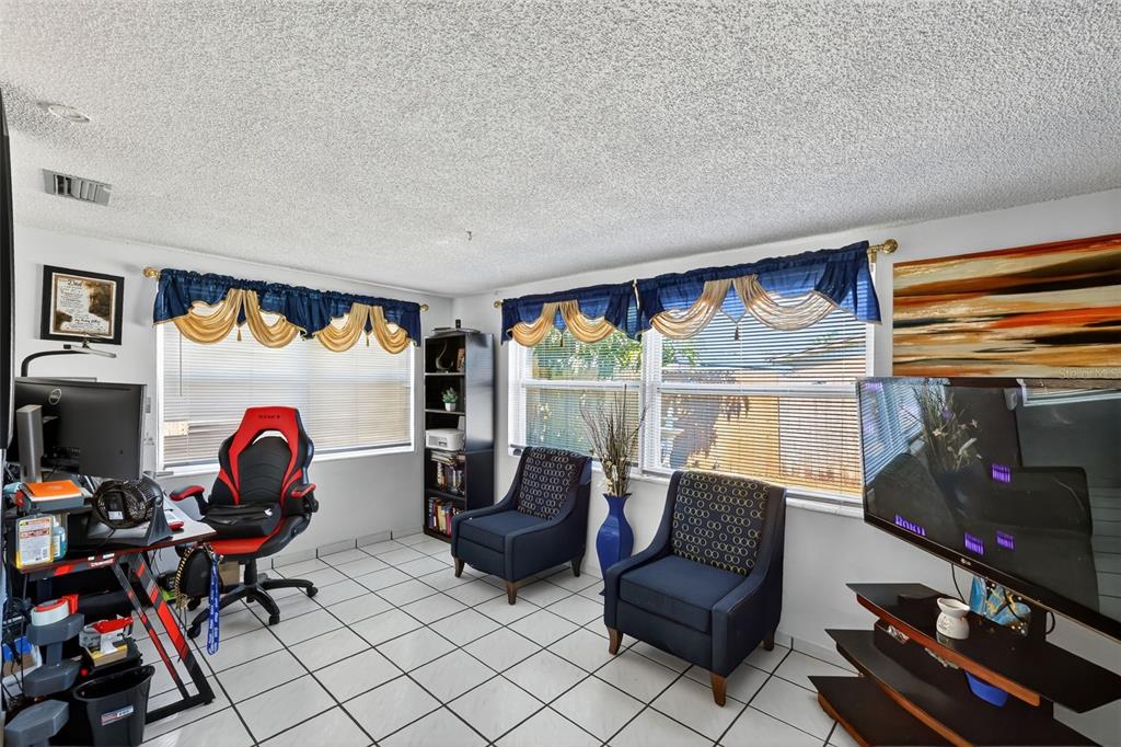3837 Darlington Road Holiday, FL 34691 - Photo 11 of 28 a living room with furniture a flat screen tv and a floor to ceiling window
