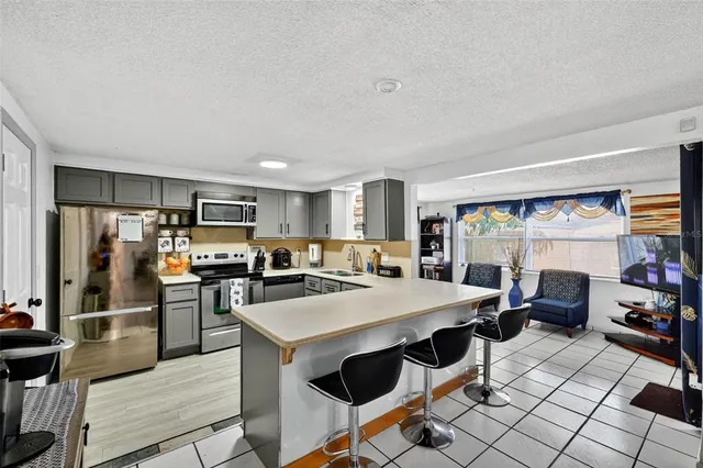 a kitchen with stainless steel appliances kitchen island granite countertop a refrigerator a stove top oven and a dining table with wooden floor