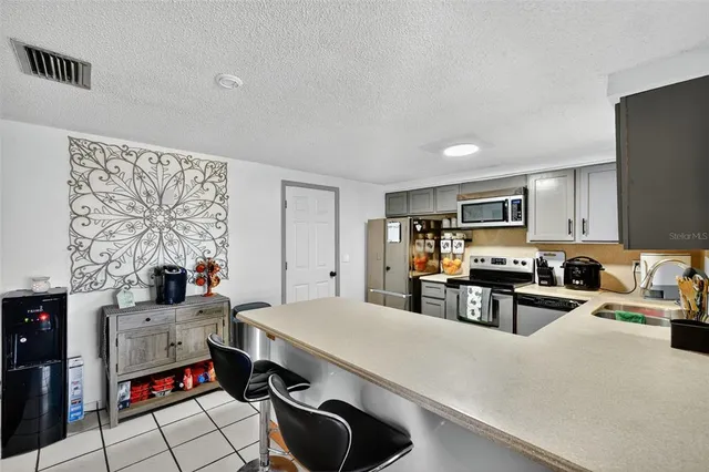 a kitchen with stainless steel appliances a stove a sink a refrigerator cabinets and dining table