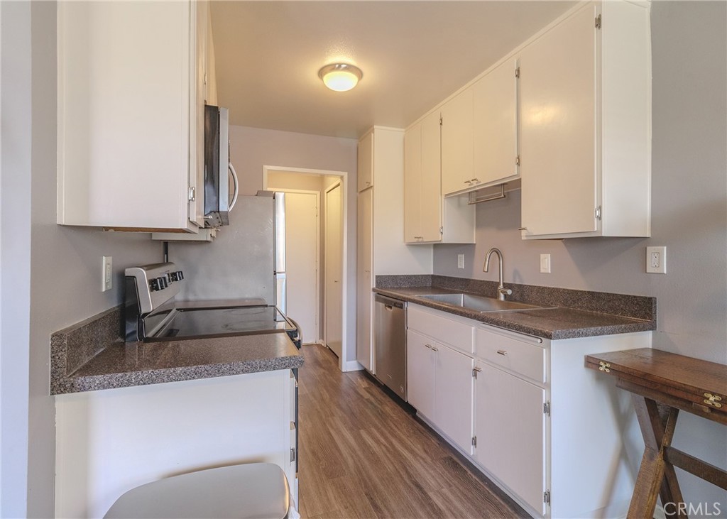 a kitchen with granite countertop a sink stove and refrigerator