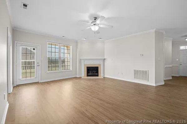 a view of an empty room with wooden floor and a fireplace