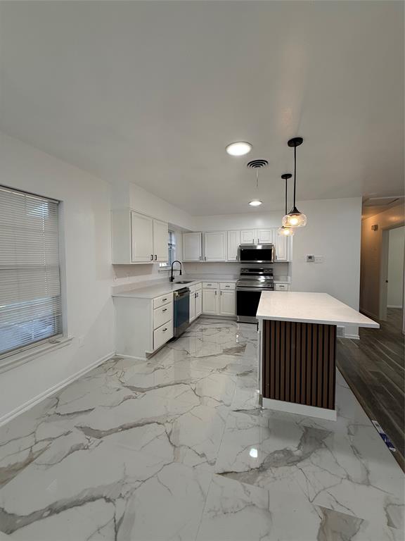 2529 Rutgers Drive Irving, TX 75062 - Photo 17 of 38 Modern kitchen with white cabinetry and an oversized island featuring a slatted wood-tone accent panel