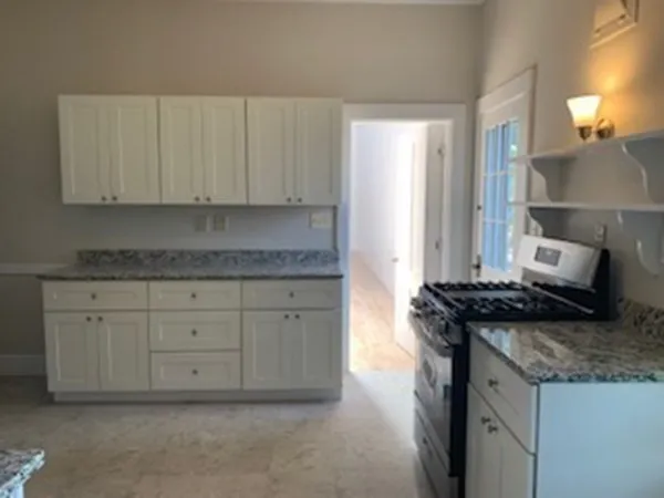 a kitchen with granite countertop a stove sink and cabinets