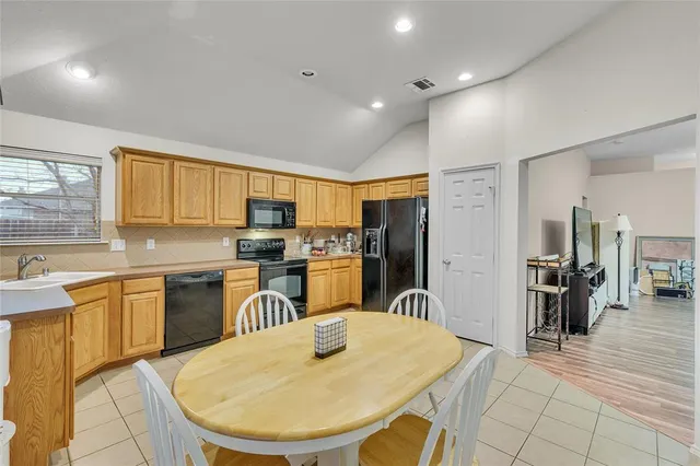 a kitchen with stainless steel appliances granite countertop a sink a stove a dining table and chairs