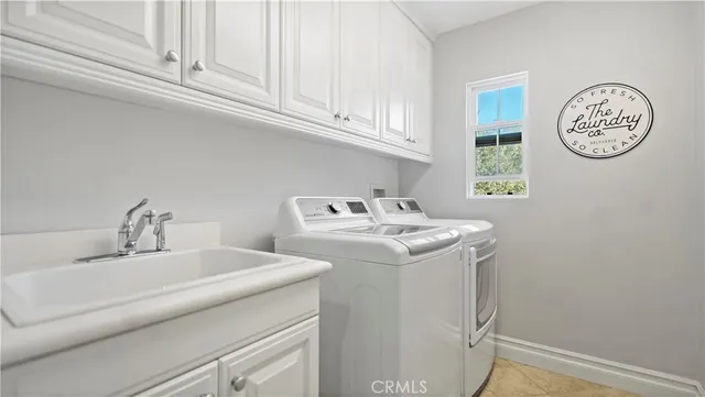 a utility room with a sink a clock and cabinets