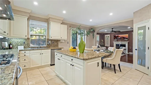 a kitchen with stainless steel appliances granite countertop a table chairs sink and cabinets