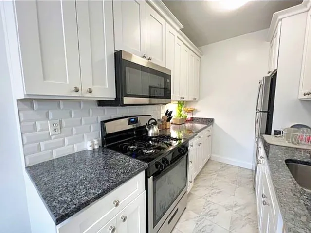 a kitchen with stainless steel appliances granite countertop a stove sink and cabinets