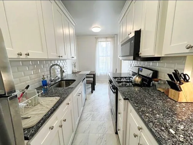 a kitchen with stainless steel appliances granite countertop a sink stove and cabinets