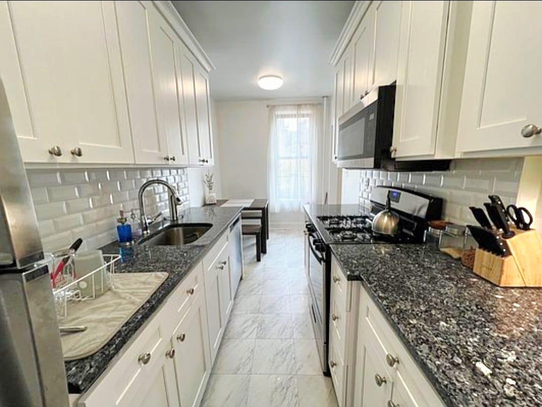83-64 Talbot Street, Unit 4B Queens, NY 11415 - Photo 6 of 16 a kitchen with stainless steel appliances granite countertop a sink stove and cabinets