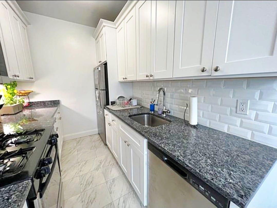 83-64 Talbot Street, Unit 4B Queens, NY 11415 - Photo 7 of 16 a kitchen with stainless steel appliances granite countertop a sink stove and cabinets