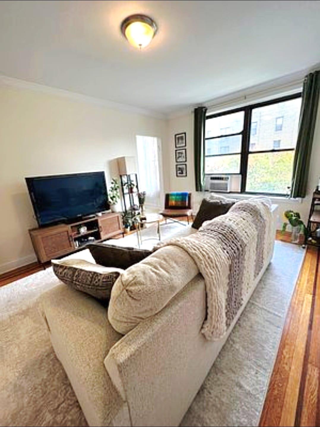 83-64 Talbot Street, Unit 4B Queens, NY 11415 - Photo 8 of 16 a living room with furniture and a large window