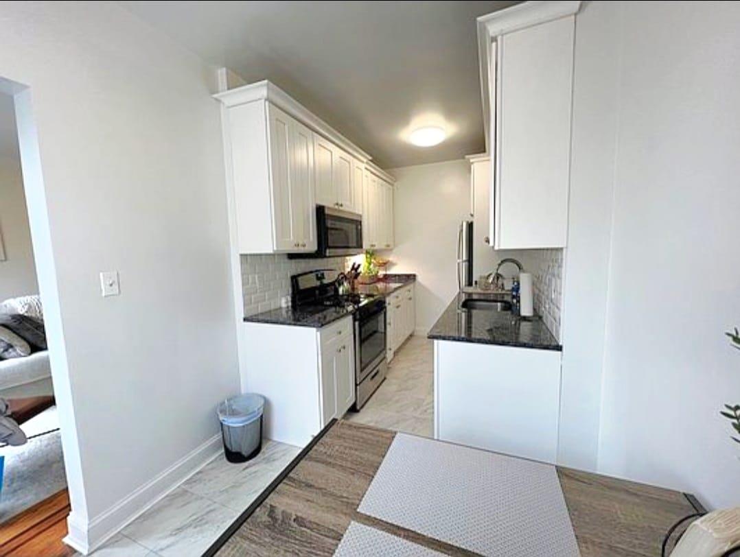 83-64 Talbot Street, Unit 4B Queens, NY 11415 - Photo 10 of 16 a kitchen with a sink and wooden cabinets