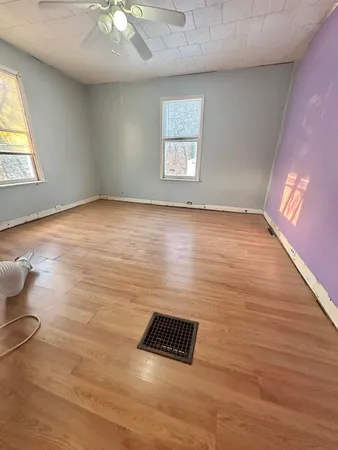 an empty room with wooden floor and windows