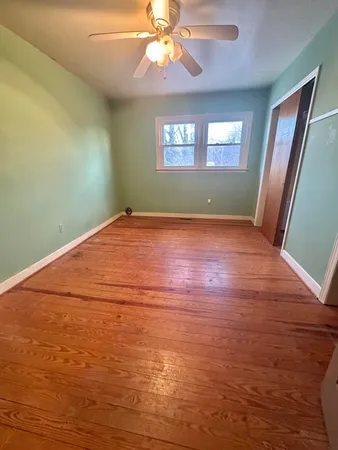 a view of an empty room with window and wooden floor